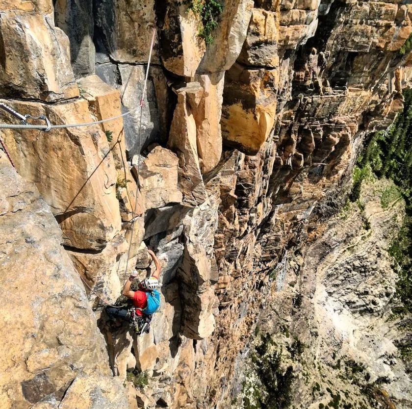 Escalador con chaqueta roja en una pared vertical de Ordesa
