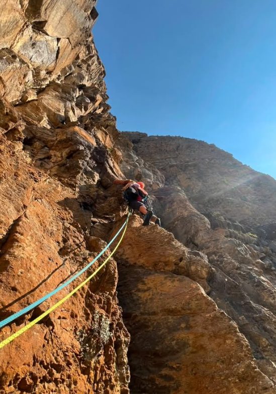 Escalador en una pared de roca naranja de Ordesa con las cuerdas de colores
