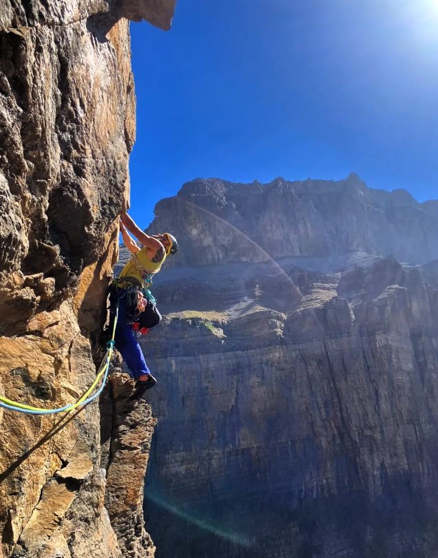 Escalador en una pared del valle de Ordesa con las grandes paredes del cañón al fondo