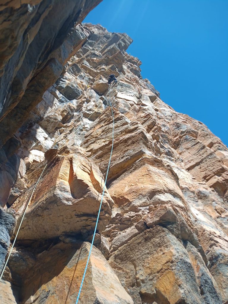 Pared de roca naranja y gris de Ordesa vista desde abajo con la cuerda de escalada