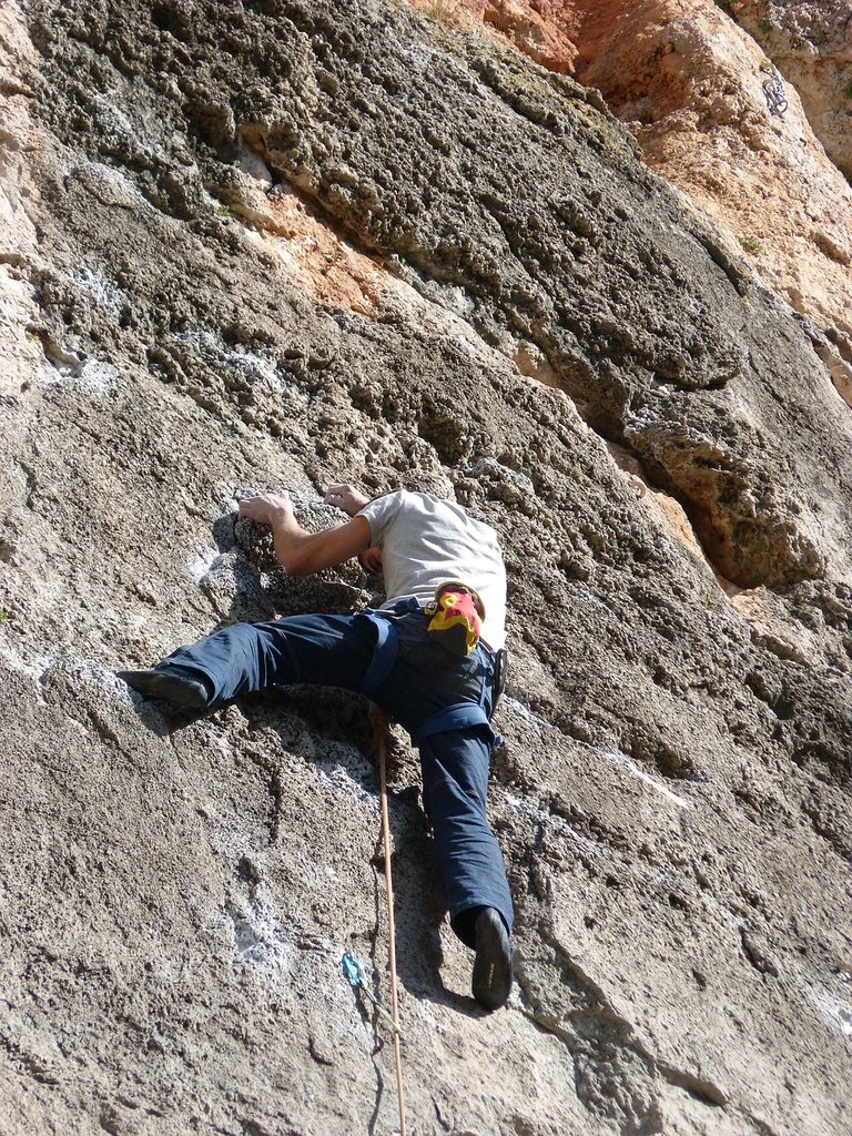 Escalador en una placa de roca gris con bolsillos en Siurana